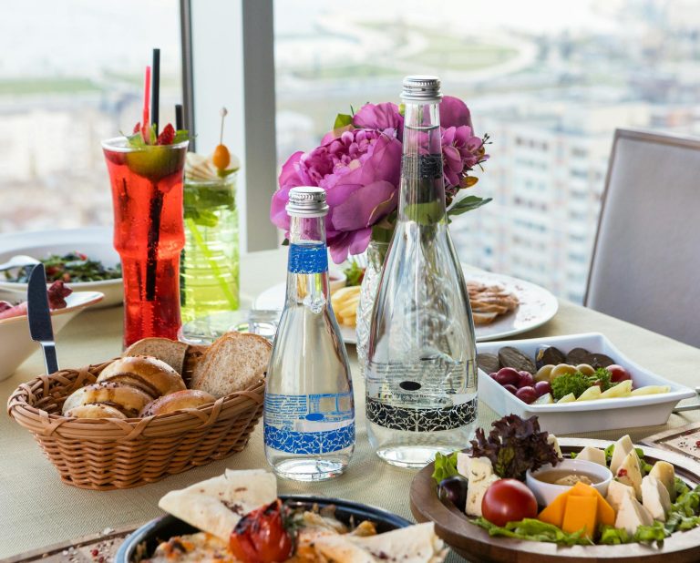 A luxurious dining table set with gourmet food and drinks overlooking a beautiful cityscape.