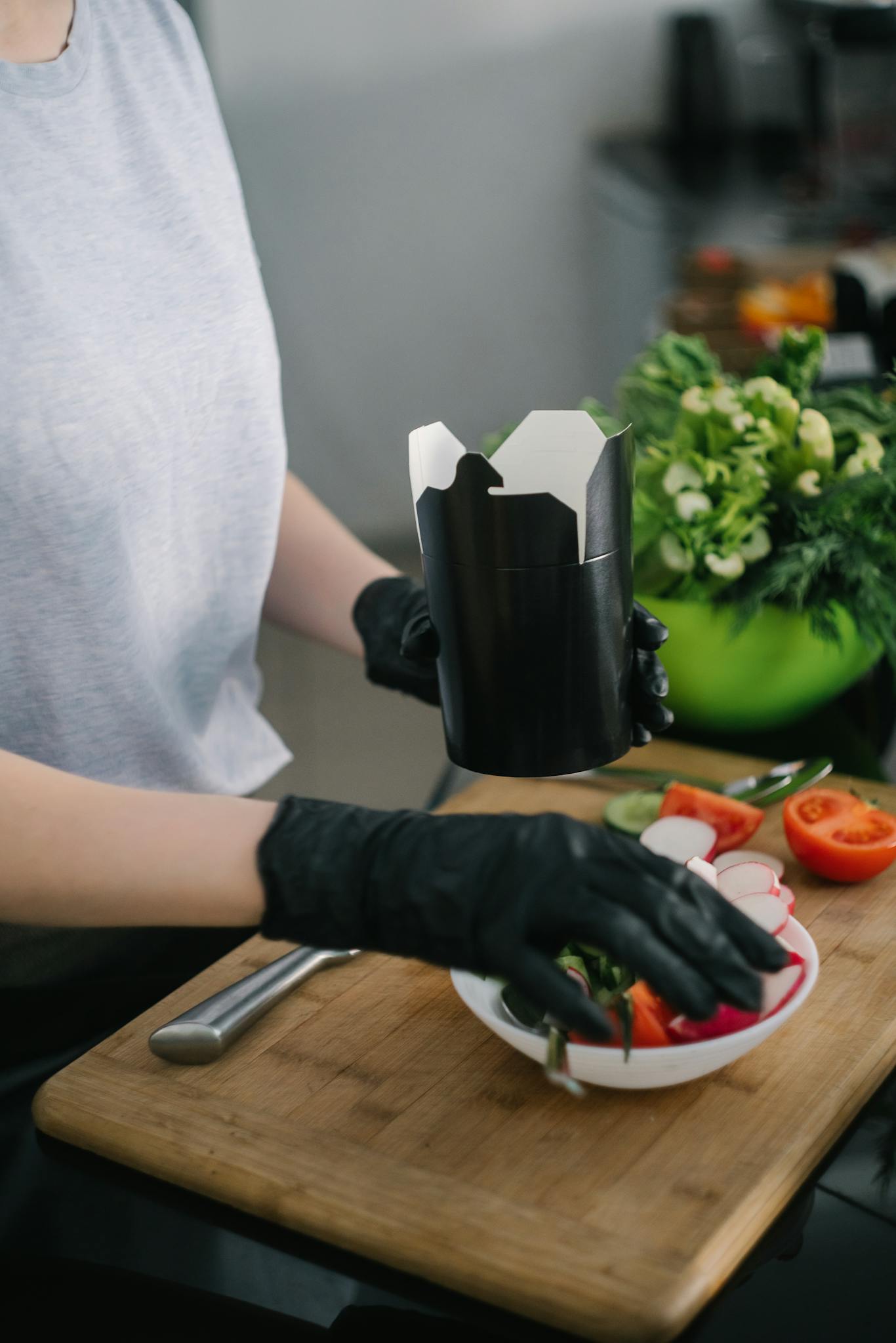 Person preparing a fresh salad meal with vegetables in a modern kitchen setting.